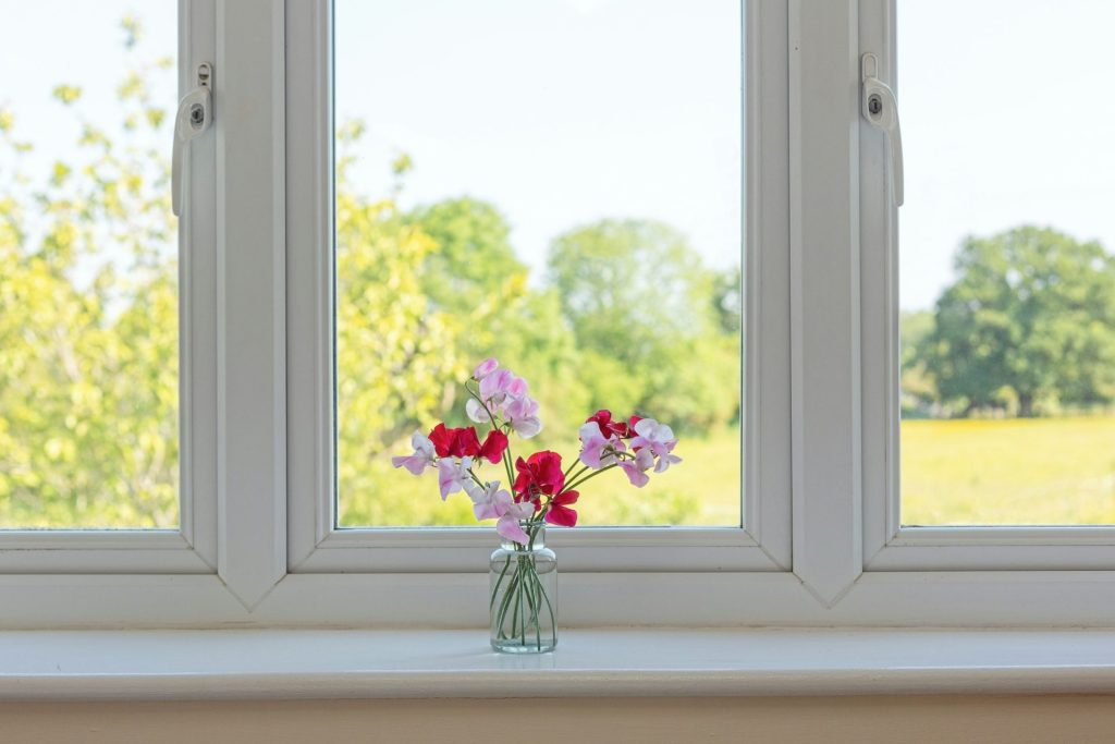 un vase rempli de fleurs posé sur le rebord d'une fenêtre